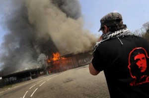 An anti-NATO protestor takes a photograph of the smashed and burning former border police station between Strasbourg and Kehl during a rally against the NATO summit in Strasbourg